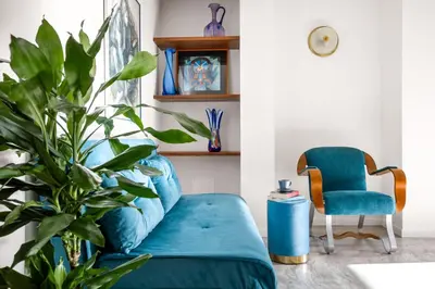 a blue couch and a chair in a room with a plant at Blu House in Terrasini