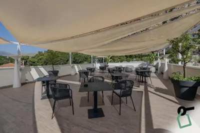 a patio with tables and chairs on a roof at HOTIDAY Mondello Beach in Mondello