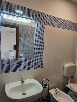 a bathroom with a sink and a mirror and a toilet at Casa vacanze mare Rosa in Castellammare del Golfo
