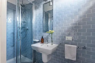 a blue tiled bathroom with a sink and a shower at La Terrazza sul Massimo in Palermo