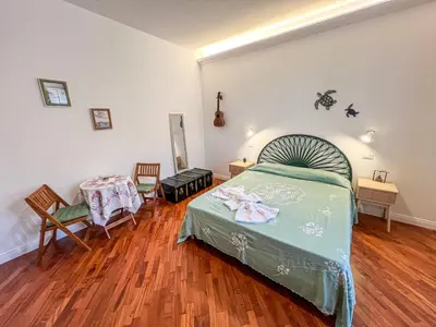 a bedroom with a green bed and wooden floors at B&B Il Mare di Terrasini in Terrasini