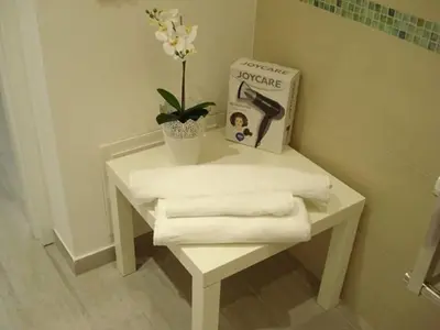 a white table with towels and a book and a plant at Appartamento Cantieri-Porto,Palermo in Palermo