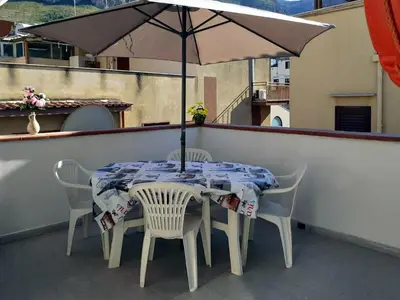 a table and chairs with an umbrella on a balcony at Don Vito's Apartments in Castellammare del Golfo