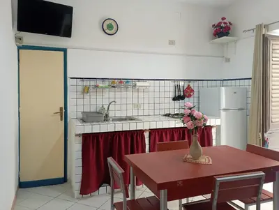 a kitchen with a table with a vase of flowers on it at Don Vito's Apartments in Castellammare del Golfo
