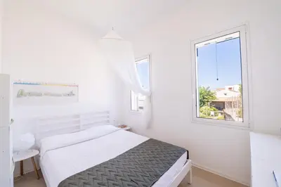 a white bedroom with a bed and a window at La Bougainvillea casa vacanze in Alcamo