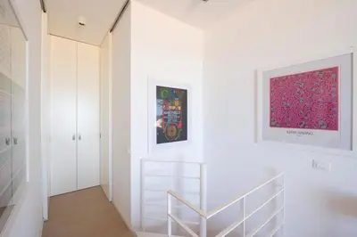 a white hallway with a staircase and a painting on the wall at La Bougainvillea casa vacanze in Alcamo