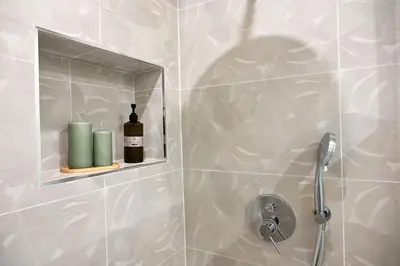 a bathroom with a shower with a soap bottle on a shelf at Chez Moi in Palermo