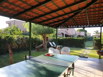 a ping pong table and chairs under a pergola at Casa delle Salinelle in Lascari