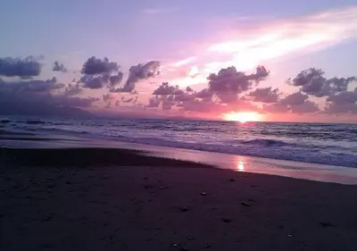 a sunset on a beach with the ocean at Casa delle Salinelle in Lascari