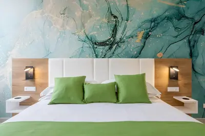 a bedroom with a large bed with a painting on the wall at Julia's Boutique Rooms in Palermo