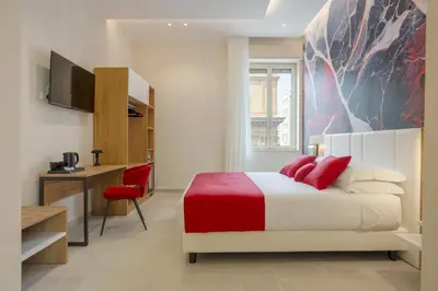 a bedroom with a bed and a desk and a television at Julia's Boutique Rooms in Palermo