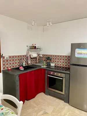 a kitchen with red cabinets and a stove and refrigerator at La mia Casetta al Politeama in Palermo