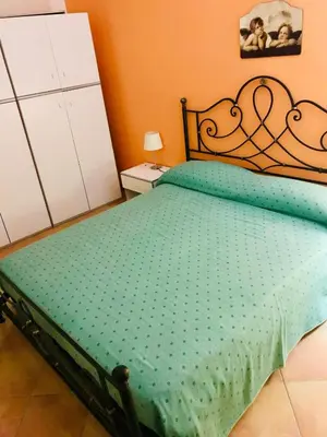 a bedroom with a bed with a green comforter at Villetta giardino, piscina, mare in Campofelice di Roccella