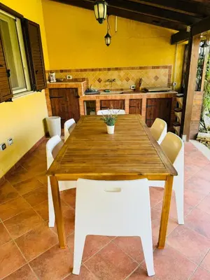 a wooden table and white chairs in a kitchen at Villetta giardino, piscina, mare in Campofelice di Roccella