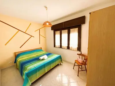 a bedroom with a bed and a chair and a window at Casa Amodei 1 a pochi passi dal mare in San Vito lo Capo