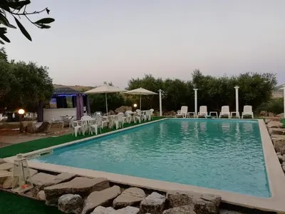 a swimming pool with tables and chairs in a yard at Casale di Riena in Lercara Friddi