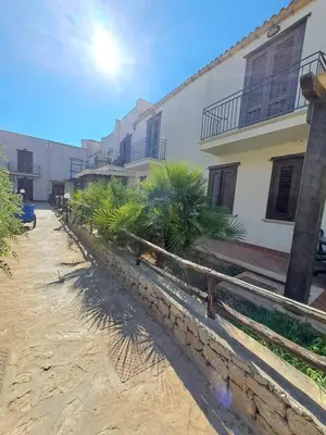 a building with palm trees in front of it at Casa Tonnarella San Vito Lo Capo in San Vito lo Capo