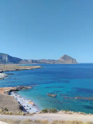 a beach with blue water and mountains in the background at Katia Home - San Vito lo Capo in San Vito lo Capo