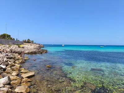 a beach with rocks and the blue water at Katia Home - San Vito lo Capo in San Vito lo Capo