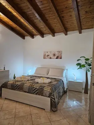 a bedroom with a large bed with a wooden ceiling at la casetta del baglio in Monreale