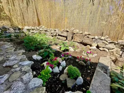a garden with flowers and rocks and a stone wall at History and Art Casa Bellacera in Casteldaccia