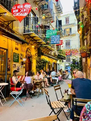 a group of people sitting at tables at an outdoor restaurant at Vucciria Holiday - Centro storico - via Emanuele in Palermo