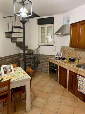 a kitchen with a table and a spiral staircase at Vucciria Holiday - Centro storico - via Emanuele in Palermo
