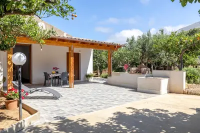 a patio with a table and chairs and trees at Case Vacanza Loria in Castelluzzo