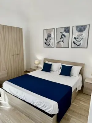 a bedroom with a large bed with blue sheets at Terrasini Center Apartments in Terrasini