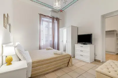 a white bedroom with a bed and a tv at GuestHost - La Rosa di Ballarò Palermo Apartment in Palermo