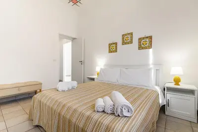 a white bedroom with a bed with towels on it at GuestHost - La Rosa di Ballarò Palermo Apartment in Palermo