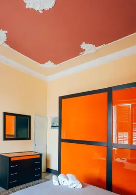 a bedroom with orange walls and a bed and a tv at Kalsa Apartment in Palermo
