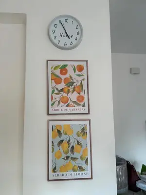 three framed pictures of oranges on a wall with a clock at Molo Sbrijù - Palermo Centro in Palermo