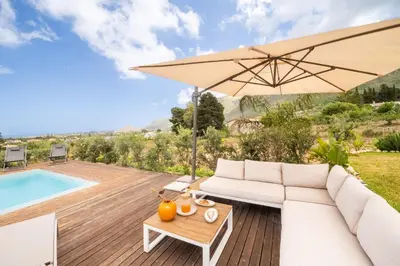 a patio with a white couch and an umbrella at Villa Manù country house in Castellammare del Golfo