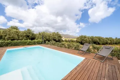 a swimming pool on a wooden deck with two chairs at Villa Manù country house in Castellammare del Golfo