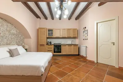 a bedroom with a white bed and a kitchen at Alabardieri Apartments by Wonderful Italy in Palermo