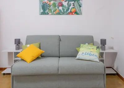 a gray couch with yellow pillows in a living room at Terrasini Downtown Little Square in Terrasini