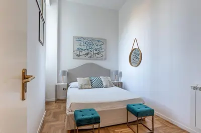 a white bedroom with a bed and two blue stools at La Casa al Foro Vista Mare by Wonderful Italy in Palermo