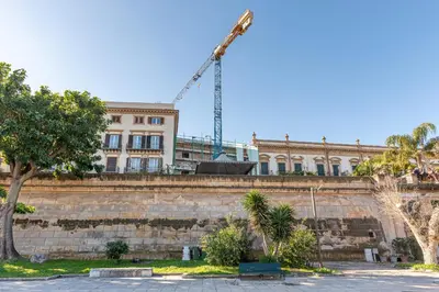 a building with a crane in the background with trees at La Casa al Foro Vista Mare by Wonderful Italy in Palermo