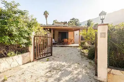 a house with a gate in front of a yard at Villa Rossa by Sicily Travelling Villas in Scopello