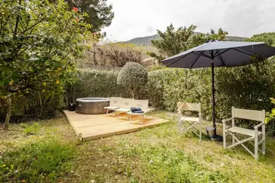 a patio with an umbrella and two chairs and a hot tub at Villa Bianca by Sicily Travelling Villas in Castellammare del Golfo