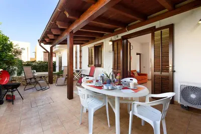 a white table and chairs on a patio with a table and a table and chairs at Trilocale Piano Terra Con Veranda in San Vito lo Capo