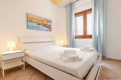 a white bedroom with a bed and a window at Villa Disa by Sicily Travelling Villas in Castellammare del Golfo