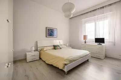 a white bedroom with a bed and a television at Chez Gabriel by DomuSicily in Palermo