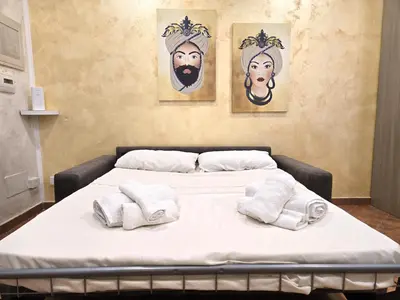 a hospital bed with towels on it with three paintings at Maison Cattedrale - Proppro SRL - Palermo in Palermo