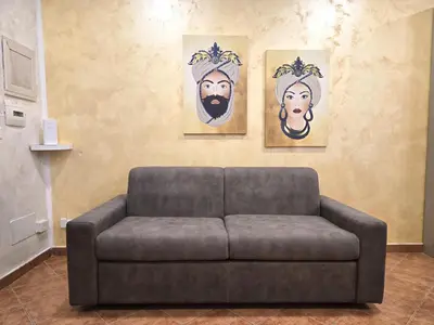 a couch in a living room with three paintings on the wall at Maison Cattedrale - Proppro SRL - Palermo in Palermo