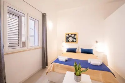 a bedroom with two beds and a window at Opera Suite in Castellammare del Golfo