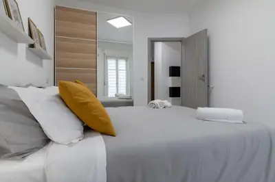 a white bedroom with a large white bed with yellow pillows at GuestHost - Sicilian Dream - Modern Central Apartment in Palermo