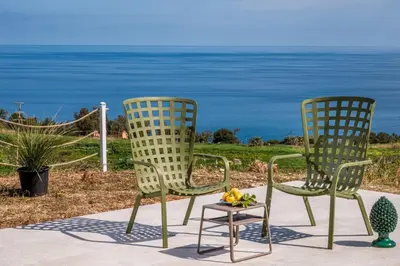 two chairs and a table with a bowl of fruit at Villa Orizzonte in Scopello