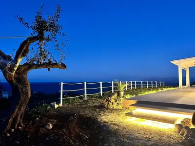 a house with a tree and a fence at night at Villa Orizzonte in Scopello